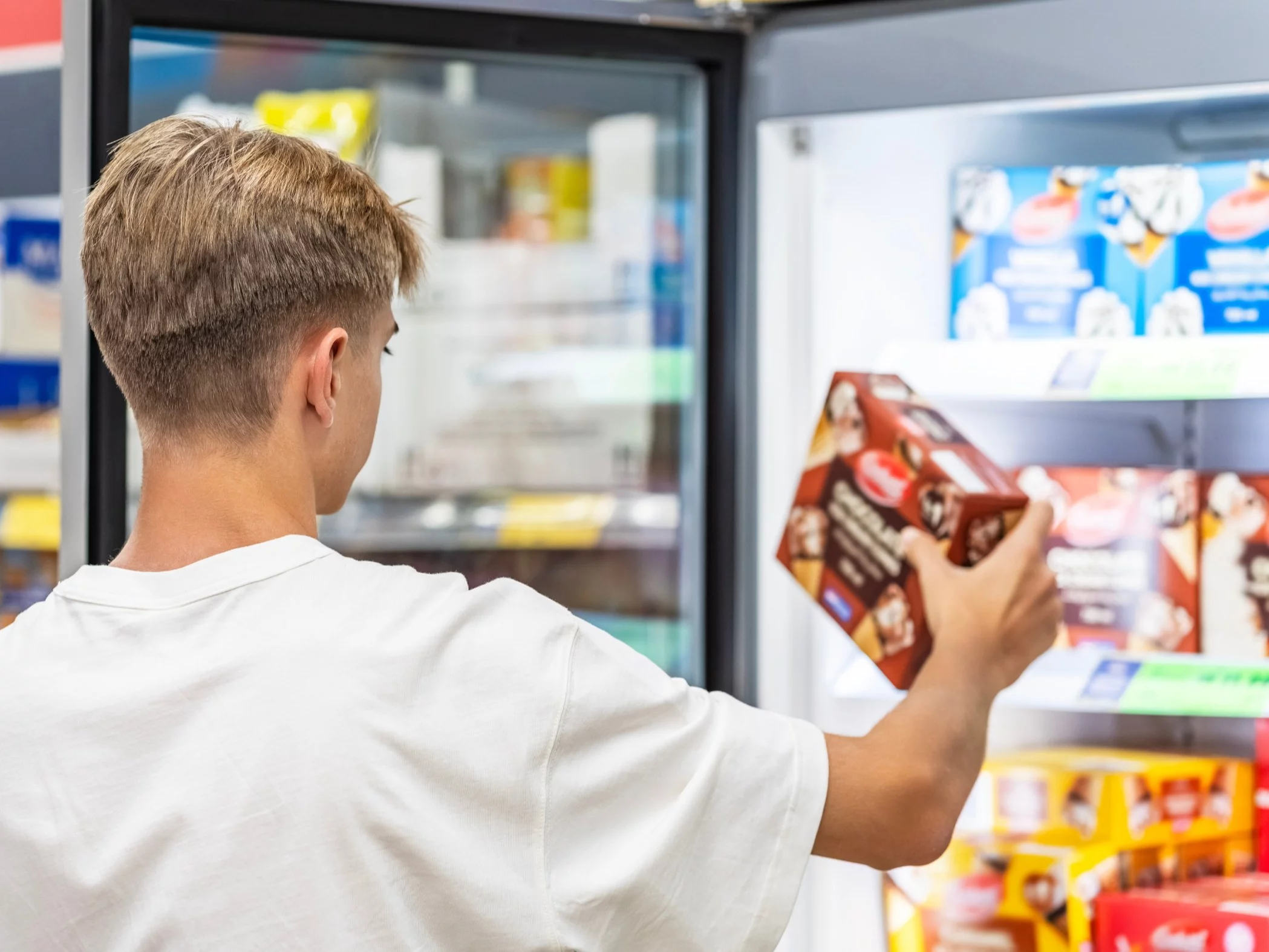 Mężczyzna wybiera lody w supermarkecie