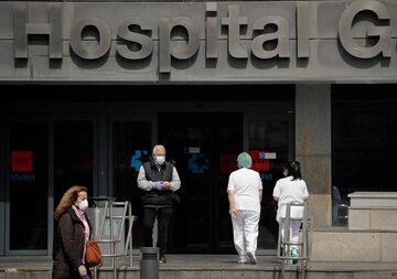 Ludzie w maseczkach przed szpitalem w Madrycie