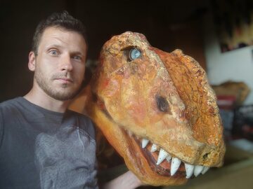 Mateusz Kowalski z głową kostiumu tyranozaura