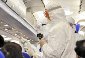 Medycy w kombinezonach ochronnych sprawdzają pasażerów w poszukiwaniu objawów koronawirusa