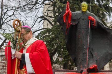 Metropolita łódzki arcybiskup Grzegorz Ryś podczas obchodów Niedzieli Palmowej, w tle oblany farbą pomnik Jana Pawła II