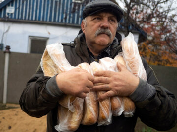 Mieszkaniec Chersonia z bochenkami chleba od wolontariuszy, 21 listopada