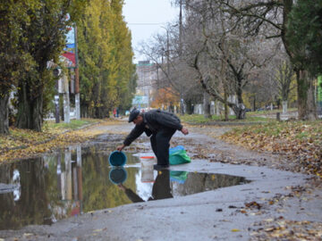 Mieszkaniec Chersonia zbiera wodę z kałuży, zdjęcie ilustracyjne