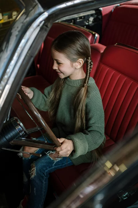 Woman in Green and Brown Striped Long Sleeve Shirt Sitting on Red Leather Vehicle Seat