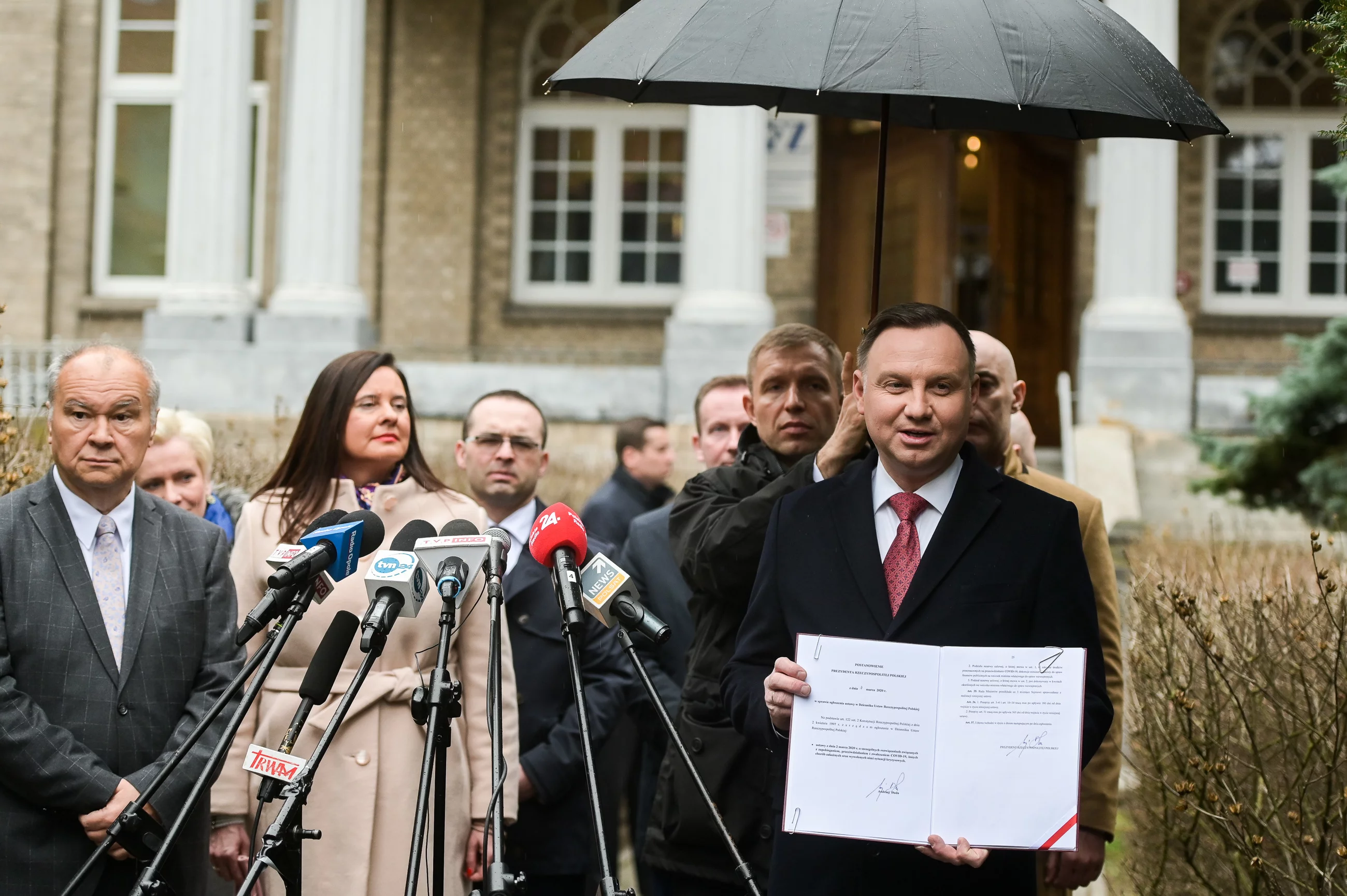 Prezydent Andrzej Duda pokazuje podpisaną specustawę, która ma pomóc w walce z koronawirusem