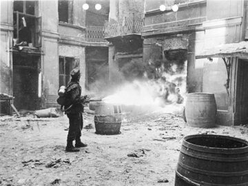 Niemiecki żołnierz podpala kamienicę w Warszawie przy użyciu miotacza płomieni.