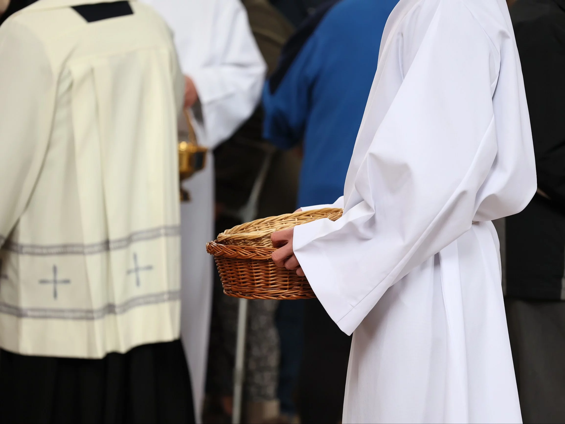 Ministrant zbiera w koszyku datki od wiernych w Kościele katolickim, zdjęcie ilustracyjne
