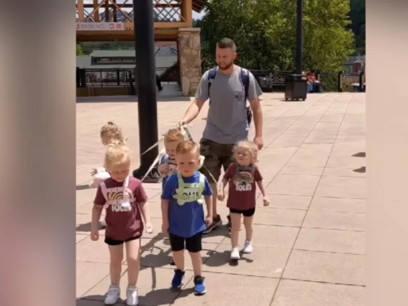 Ojciec prowadzi dzieci na smyczy