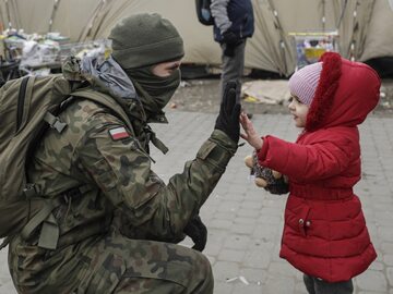 Polski żołnierz i ukraińska dziewczynka na przejściu granicznym w Medyce
