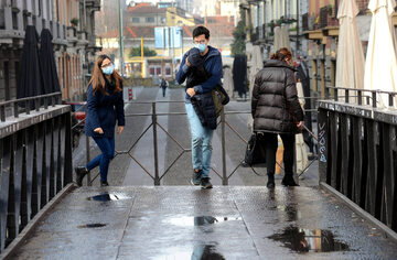 Przechodnie w maskach na ulicy Mediolanu, zdjęcie ilustracyjne