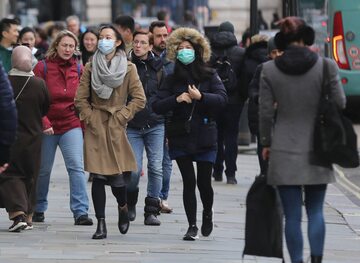 Przechodnie w maskach ochronnych na ulicach Londynu