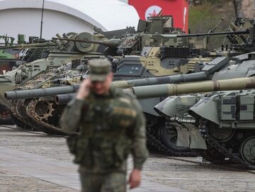Rosyjski żołnierz przechodzi przed pojazdami opancerzonymi