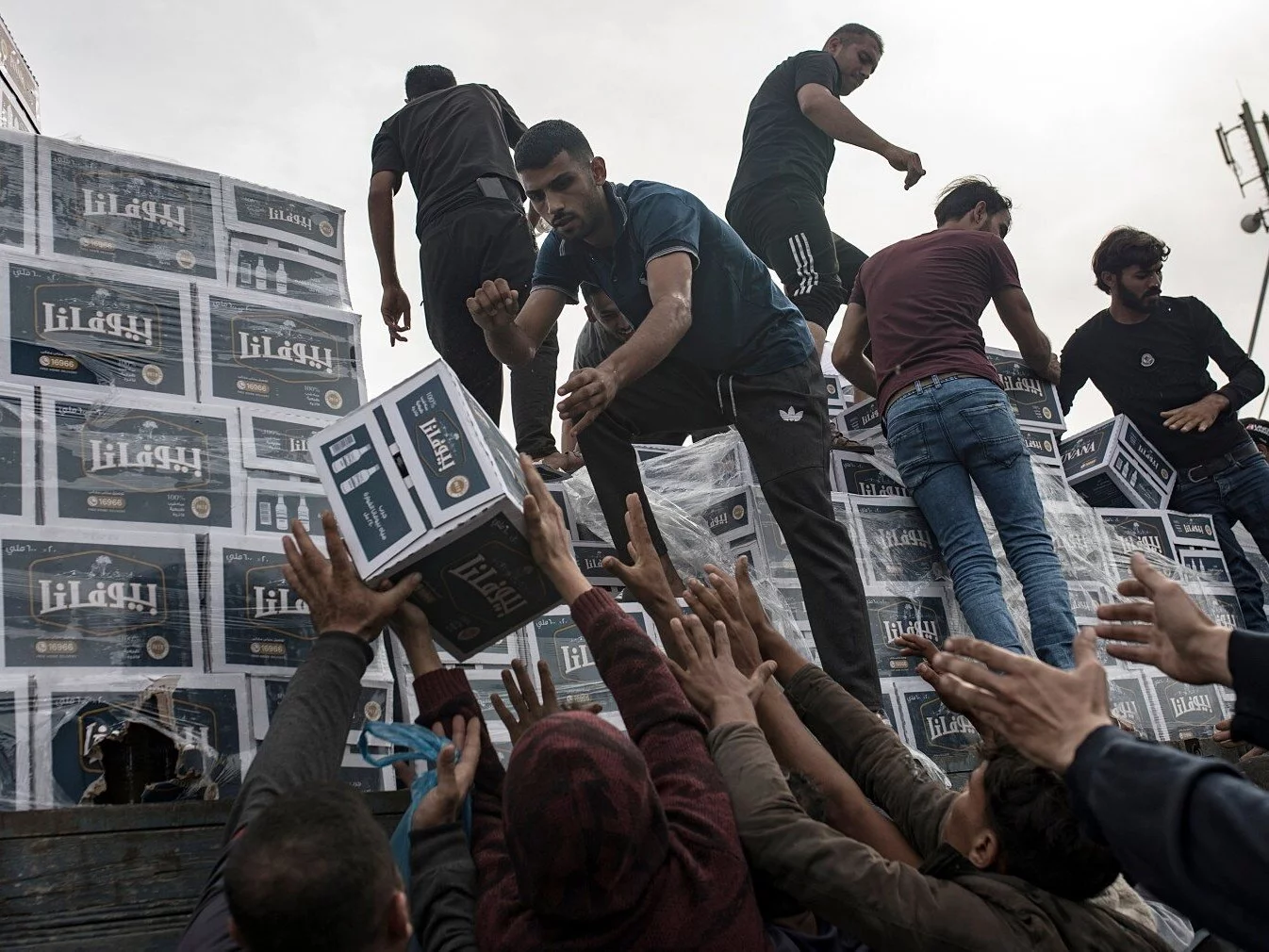 Pomoc humanitarna, w tym woda, rozdawana Palestyńczykom ewakuującym się do południowej Strefy Gazy