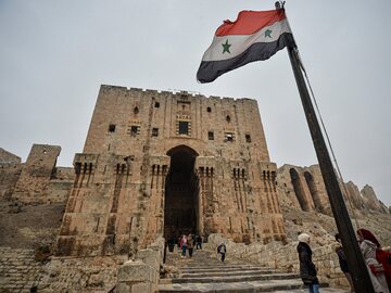 Syria. Rządowa flaga nad uszkodzoną podczas wojny domowej zabytkową cytadelą w Aleppo