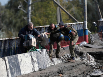 Ukraińscy żołnierze pomagają starszemu mężczyźnie w niedawno wyzwolonym Kupiańsku, 3 października