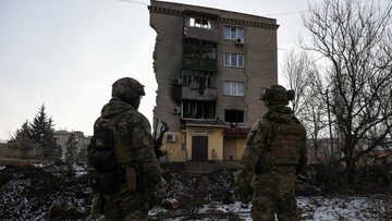 Ukraińscy żołnierze przed zniszczonym domem w Bachmucie