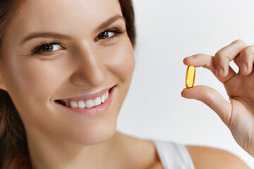 Uśmiechnięta kobieta suplementuje witaminę D