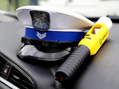 Czapka policjanta i alkomat w radiowozie, zdjęcie ilustracyjne