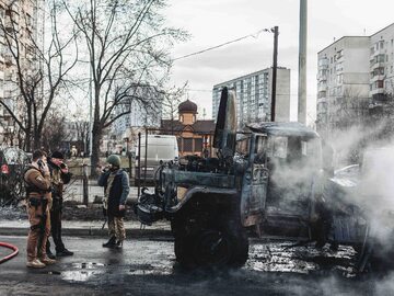 Wojna na Ukrainie. Żołnierze obok spalonego rosyjskiego pojazdu