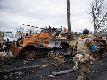 Żołnierz obok zniszczonych pojazdów i czołgów w Irpieniu, zdjęcie ilustracyjne