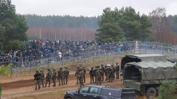 Żołnierze naprzeciwko migrantów przy granicy polsko-bialoruskiej